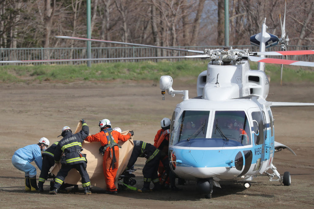 2022年4月24日，日本救援人員把遇難者從直升機轉機到救護車上。（STR/JIJI PRESS/AFP via Getty Images）
