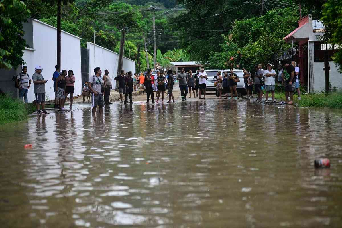 2025年10月10日,墨西哥韋拉克魯斯州波薩里卡市(Poza Rica)遭暴雨襲擊後,人們聚集在一條被洪水淹沒的街道上。(Marco Antonio Perez/AFP via Getty Images)