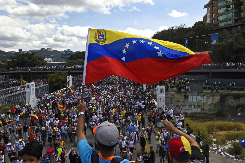 2019年2月2日，在委內瑞拉首都加拉加斯，一名反對派支持者在抗議馬杜羅政府的集會上揮舞國旗。（FEDERICO PARRA/AFP via Getty Images）