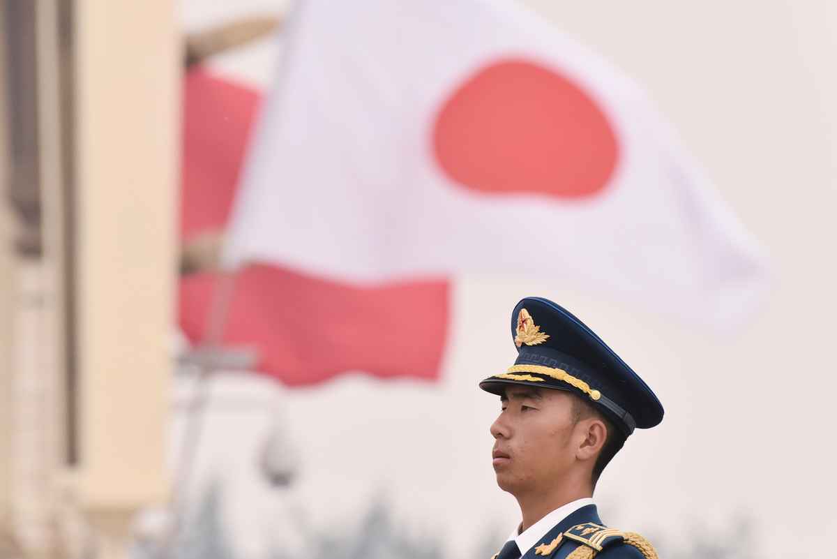 資料圖：2018年10月25日，一名中共士兵在北京天安門廣場站崗，他身後飄著日本國旗（上）和中共五星旗。當天，日本首相安倍晉三首次訪華。（GREG BAKER/AFP via Getty Images）