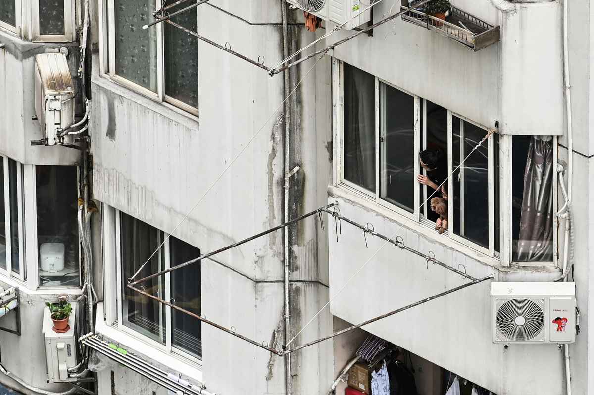 2022年4月23日，上海靜安區被封控在住宅樓的居民望向窗外。（Hector Retamal/AFP）