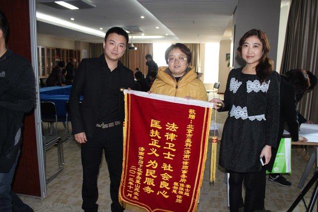 2013年11月，在北京市盈科（濟南）律師事務所大廳內，業主代表向掌士超及其團隊成員侯雅楠律師贈送錦旗，表彰掌士超律師團隊幫助學府藍山小區房產證維權事宜。（掌士超提供）