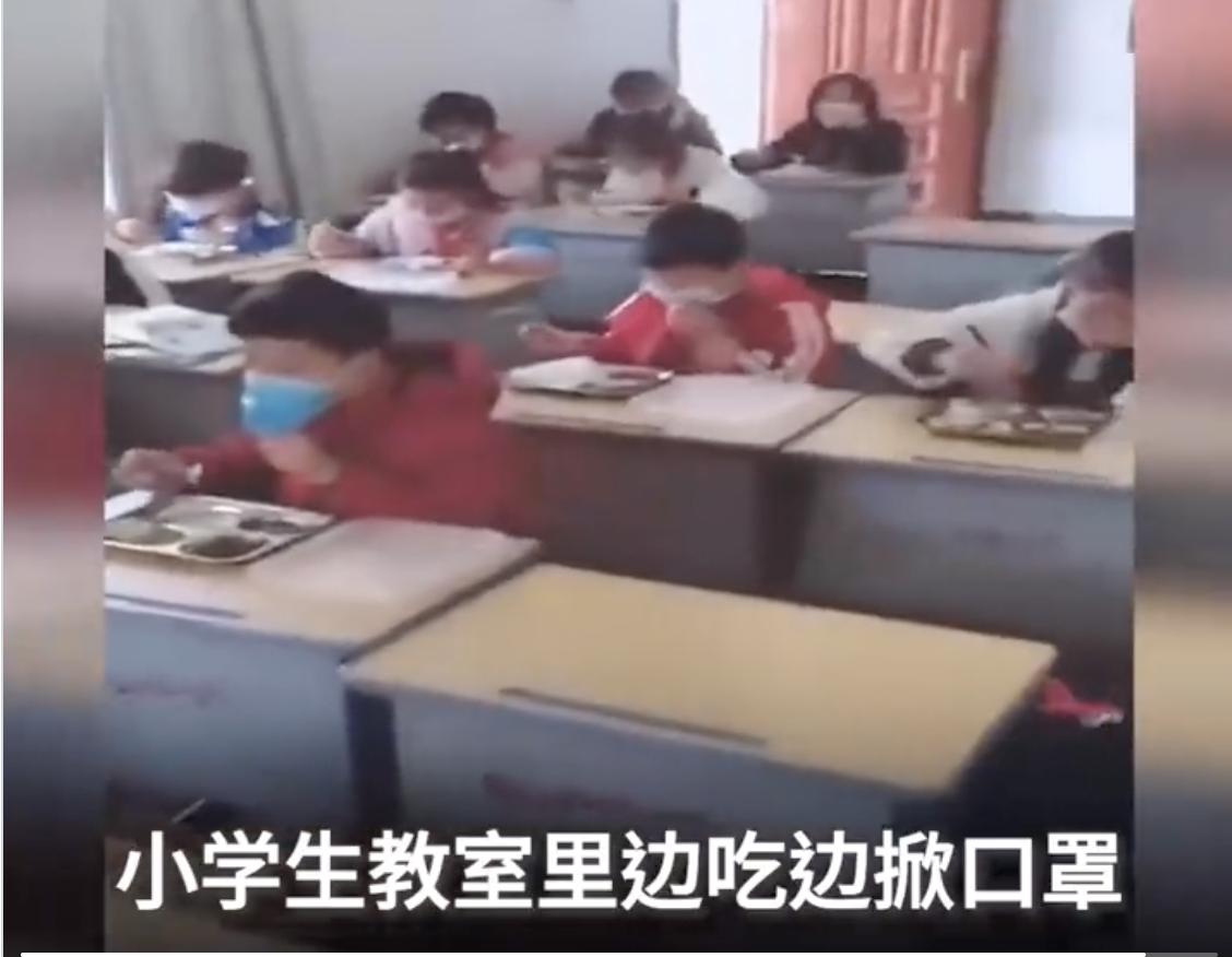 小學生在教室裏吃飯，邊吃邊掀口罩。（影片截圖）