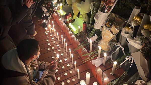 2022年11月28日，北京，在為新疆一場致命火災的受害者舉行的集會上，抗議者手持蠟燭和鮮花聚集在一條街道上，他們同時也抗議中國政府對新冠疫情的嚴格封控。（Michael Zhang/AFP via Getty Images）