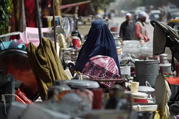 2021年9月12日，一名婦女在喀布爾西北部的一個臨時市場上，查看待售的二手家用物品。許多阿富汗人以低價出售家庭用品以換取現金，來資助他們長途跋涉逃離這個國家，或只是為了籌錢購買食物。 （WAKIL KOHSAR/AFP via Getty Images）