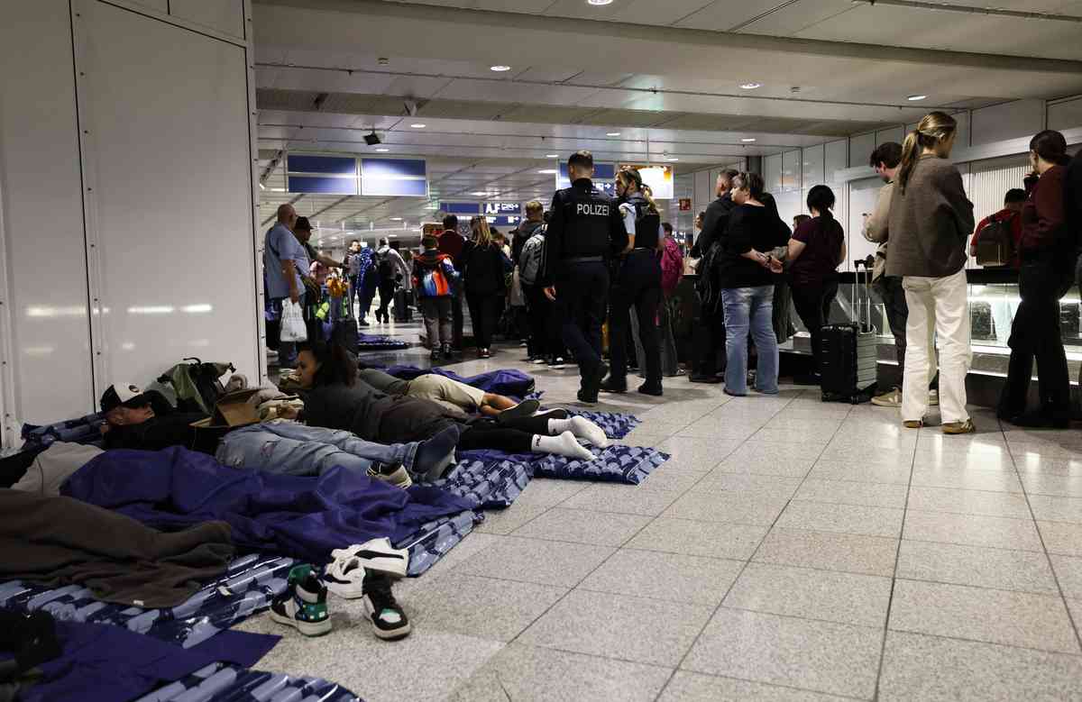 2025年10月4日清晨,德國南部慕尼黑國際機場(Munich International Airport)內,部份乘客躺在提供的充氣床墊上休息,另一些人則在旁邊排隊等候。由於接連接獲無人機目擊報告,慕尼黑機場兩度被迫關閉,航班取消,至少有6,500名乘客受到影響。(Michaela STACHE / AFP via Getty Images)