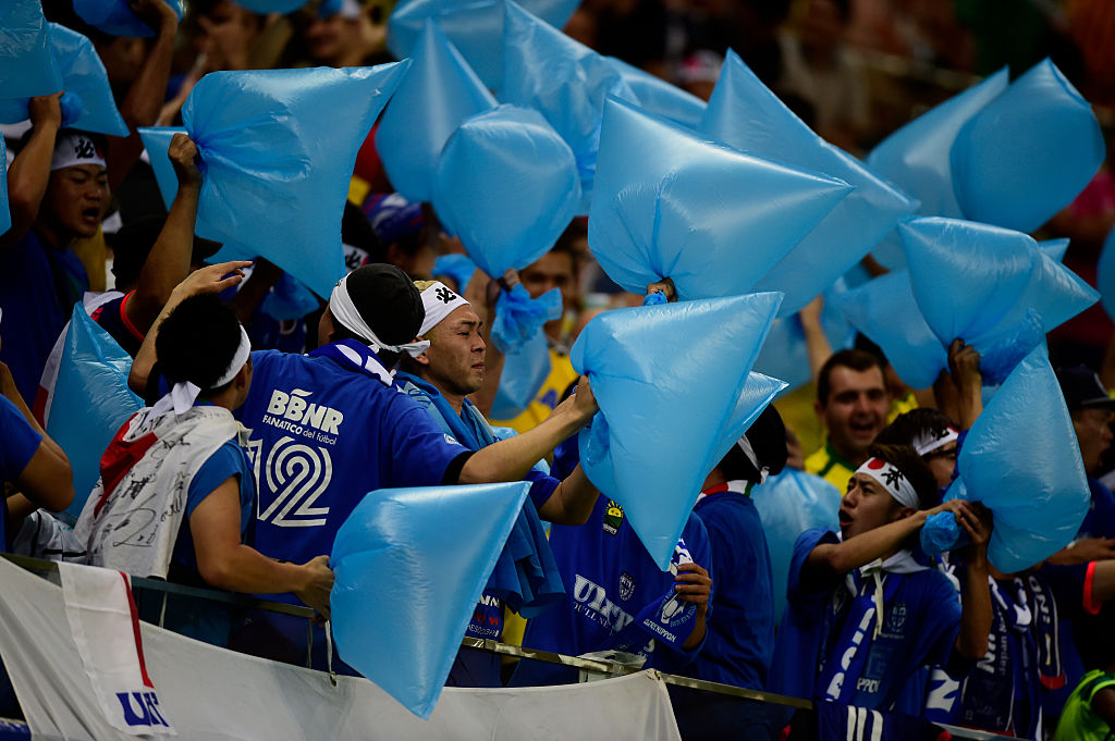 日本球迷拿著代表日本球隊顏色的藍色垃圾袋，比賽中用來給日本隊打氣，賽后用來撿垃圾。（Getty Images)