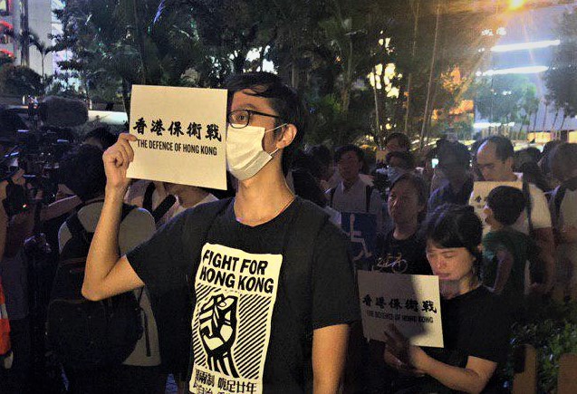 2019年8月30日晚上8點，香港民眾在中環和平紀念碑舉辦重光紀念日默站活。圖為民眾手持「香港保衛戰」標語。（梁珍／大紀元）