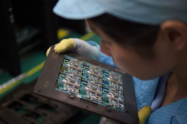 圖為東莞一名女工在查看手機晶片。資料圖。（NICOLAS ASFOURI/AFP/Getty Images）