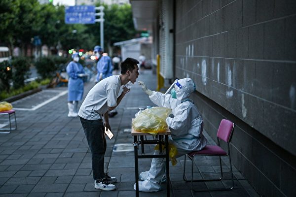 2022年7月5日，上海市靜安區的醫務人員為當地居民進行核酸檢測採集拭子樣本。（HECTOR RETAMAL/AFP via Getty Images）
