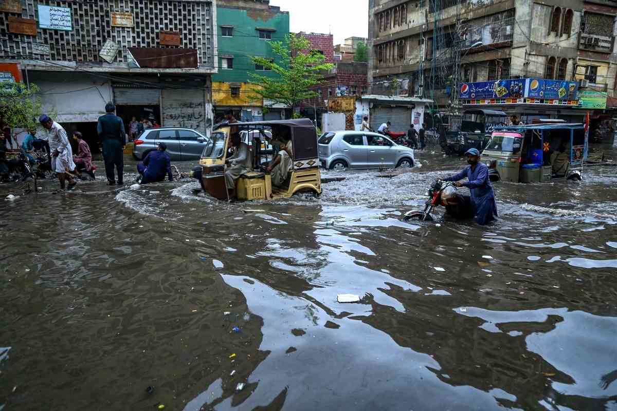 2025年7月14日,巴基斯坦信德省海得拉巴市(Hyderabad)遭暴雨襲擊後,民眾被迫涉水出行。(Jan Ali Laghari/Middle East Images/AFP via Getty Images)