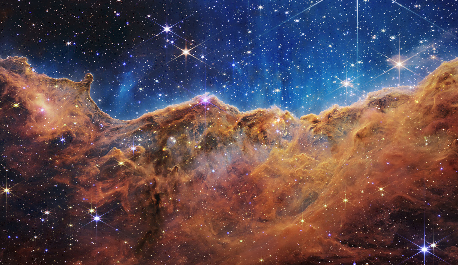 這片由「山」和「谷」組成、恆星閃爍的景觀實際上是附近一個年輕的恆星形成區域的邊緣，該區域位於船底座星雲（Carina Nebula）的NGC 3324。（NASA/ESA/CSA/STScI）