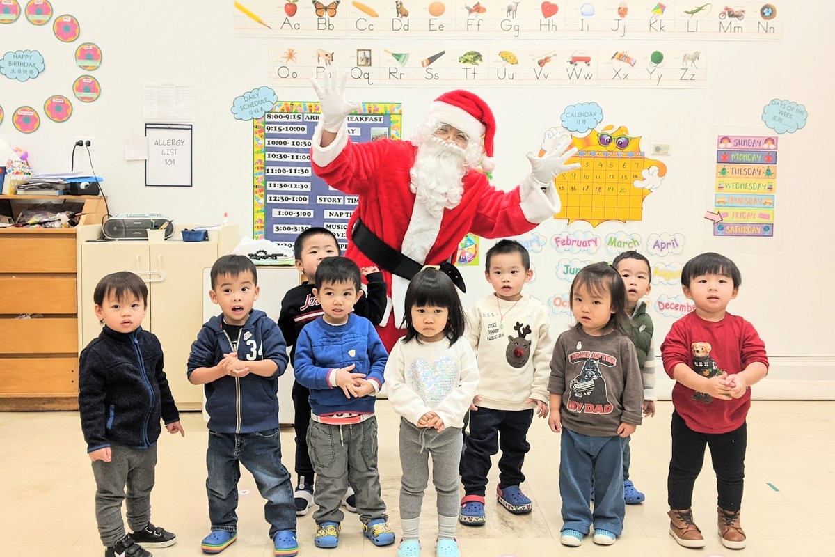 12月20日，紐約華埠兒童培護中心一年一度的聖誕老人派禮物活動，家長扮演的聖誕老人與孩子們合照。（黃小堂／大紀元）