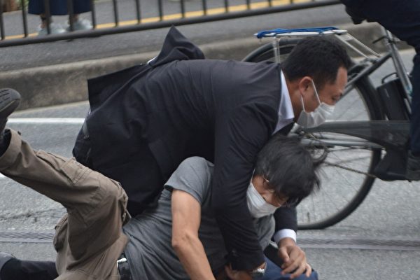 2022年7月8日，一名涉嫌槍殺日本前首相安倍晉三的男子（下）被警察撲倒在地。 （STR/Yomiuri Shimbun/AFP）