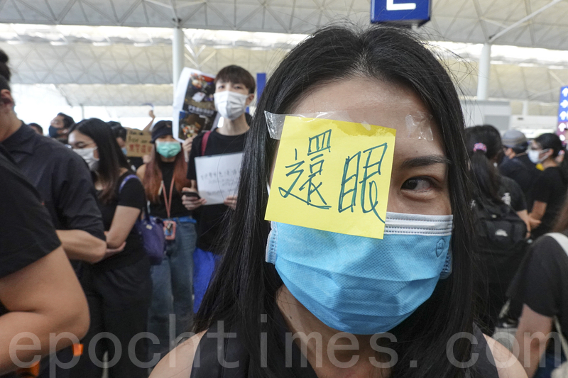 2019年8月12日，針對8.11警察在清場過程中近距離開槍致使一女示威者眼球爆裂，示威者到機場集會，同時高呼「還眼」對警察近距離射殺示威者表達憤怒。（余鋼／大紀元）