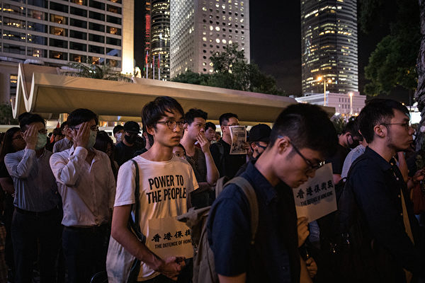 2019年8月30日晚上8點，香港民眾在中環和平紀念碑舉辦重光紀念日默站活動，參與民眾做出掩右眼手勢。（Chris McGrath/Getty Images）