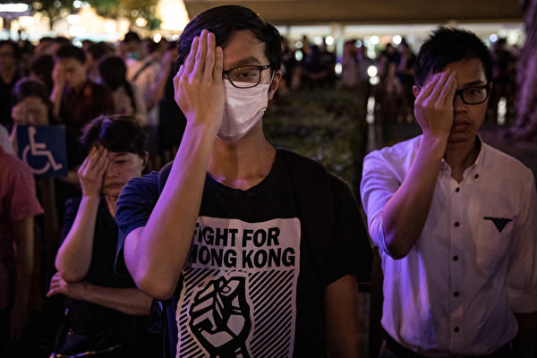 2019年8月30日晚上8點，香港民眾在中環和平紀念碑舉辦重光紀念日默站活動，參與民眾做出掩右眼手勢。（Chris McGrath/Getty Images）