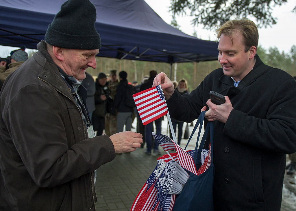 美國駐波蘭大使館的一名工作人員2017年1月12日在為抵達駐波蘭軍事基地的美軍士兵舉行的歡迎儀式上，向波蘭人贈送美國國旗。（NATALIA DOBRYSZYCKA/AFP via Getty Images）