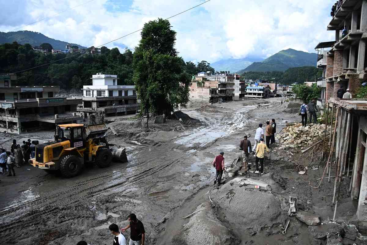 2026年8月27日，在尼泊爾努瓦科特縣（Nuwakot）特里蘇里（Trishuli）發生山洪的第二天，工人使用挖土機清理道路上的淤泥和各種垃圾。（Prakash Mathema/AFP via Getty Images）