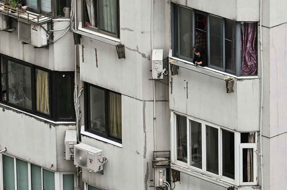 2022年4月24日，中國上海市靜安區，COVID-19（新冠病毒）疫情延燒，封城期間一位居民望向窗外。（Hector Retamal/AFP via Getty Images）