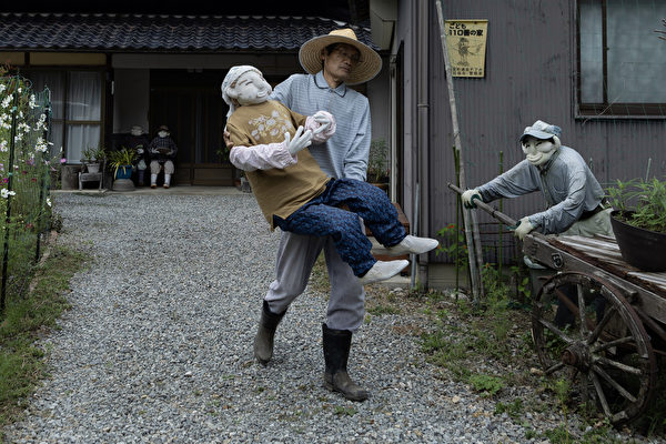 2023年9月20日,日本安富(Yasutomi),71 歲的岡上正人(Masato Okaue)在「人偶村」(Kakasi No Sato,かかしの里)抱著手工製作的稻草人,準備放置在田野中。岡上正人自2010年以來,在村莊放置了逾130個稻草人,表明村莊尚未完全荒廢。(Buddhika Weerasinghe/Getty Images)