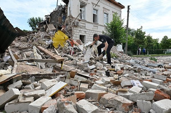  圖為2022年6月26日，俄軍火箭彈在哈爾科夫西北郊區爆炸後，一名烏克蘭警察在建築物的殘骸中搜索倖存人員。（SERGEY BOBOK/AFP）