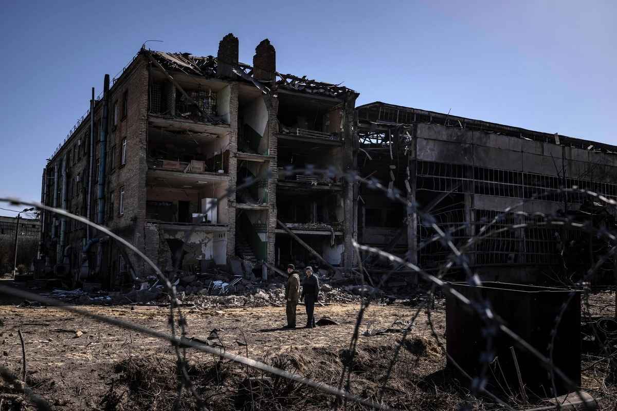 2022年4月15日，在基輔西南郊的維什內夫鎮（Vyshneve），人們站在維扎爾公司（Vizar）軍工綜合體受損建築旁。該地遭到俄羅斯連夜打擊。（FADEL SENNA/AFP via Getty Images）
