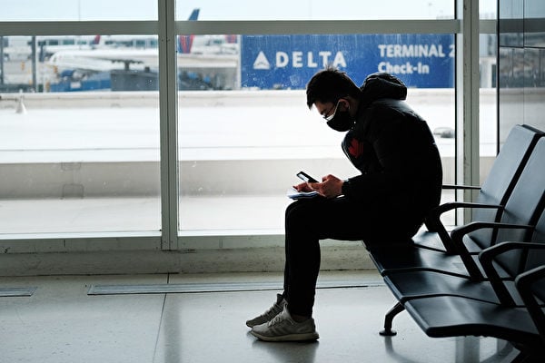2022年元旦假期，北美受疫情和惡劣天氣影響，數千航班延誤甚至取消，而許多等待返鄉團聚的華人卻因熔斷，而無機可搭。圖為機場一名戴口罩的旅客。（Spencer Platt / Getty Images）