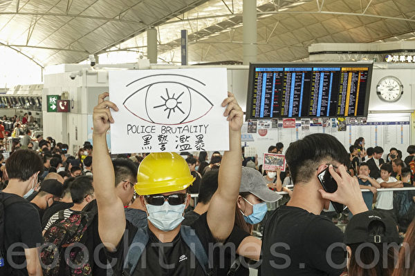 2019年8月12日，港人在香港機場展開「警察還眼」集會。圖為示威民眾舉著「黑警濫暴」的標語表達抗議。（余鋼／大紀元）