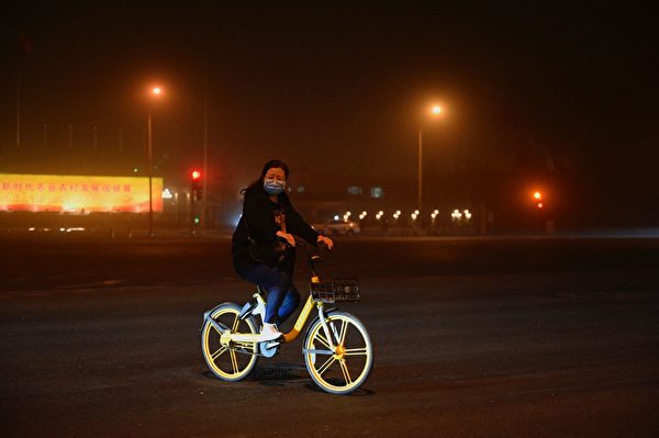 2023年4月10日晚，沙塵暴已抵達北京，市民在路上騎車。（JADE GAO/AFP via Getty Images）