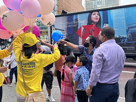 慶祝「世界法輪大法日」，法輪功學員5月13日在法拉盛派發印有「法輪大法好」的氣球，與民眾分享喜慶。（林丹／大紀元）