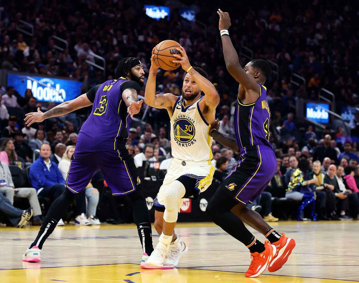 2022年10月18日，NBA新賽季揭幕戰，金州勇士在主場123:109輕取洛杉磯湖人，開啟衛冕之路。圖為勇士隊當家球星庫里（中）在夾擊下衝擊籃筐瞬間。（Ezra Shaw/Getty Images）