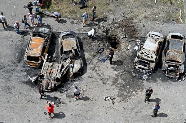 2022年6月26日，俄軍導彈擊中哈爾科夫東郊一個住宅區的庭院後，人們聚集在被摧毀的車輛附近。（SERGEY BOBOK/AFP）