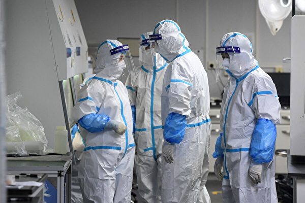 2021年8月4日，在武漢市的一個檢測機構，實驗室技術人員穿著個人防護設備，對待檢測的COVID-19病毒樣本進行檢測。（STR/AFP via Getty Images）