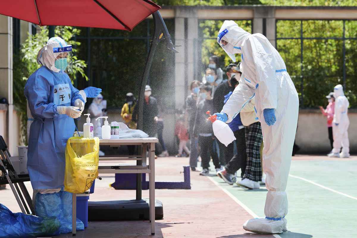 2022年4月17日，在上海浦東封鎖期間，穿著個人防護裝備的志願者對社區進行消毒，然後大院裏將開始進行COVID-19冠狀病毒的測試。（Liu Jin/AFP）