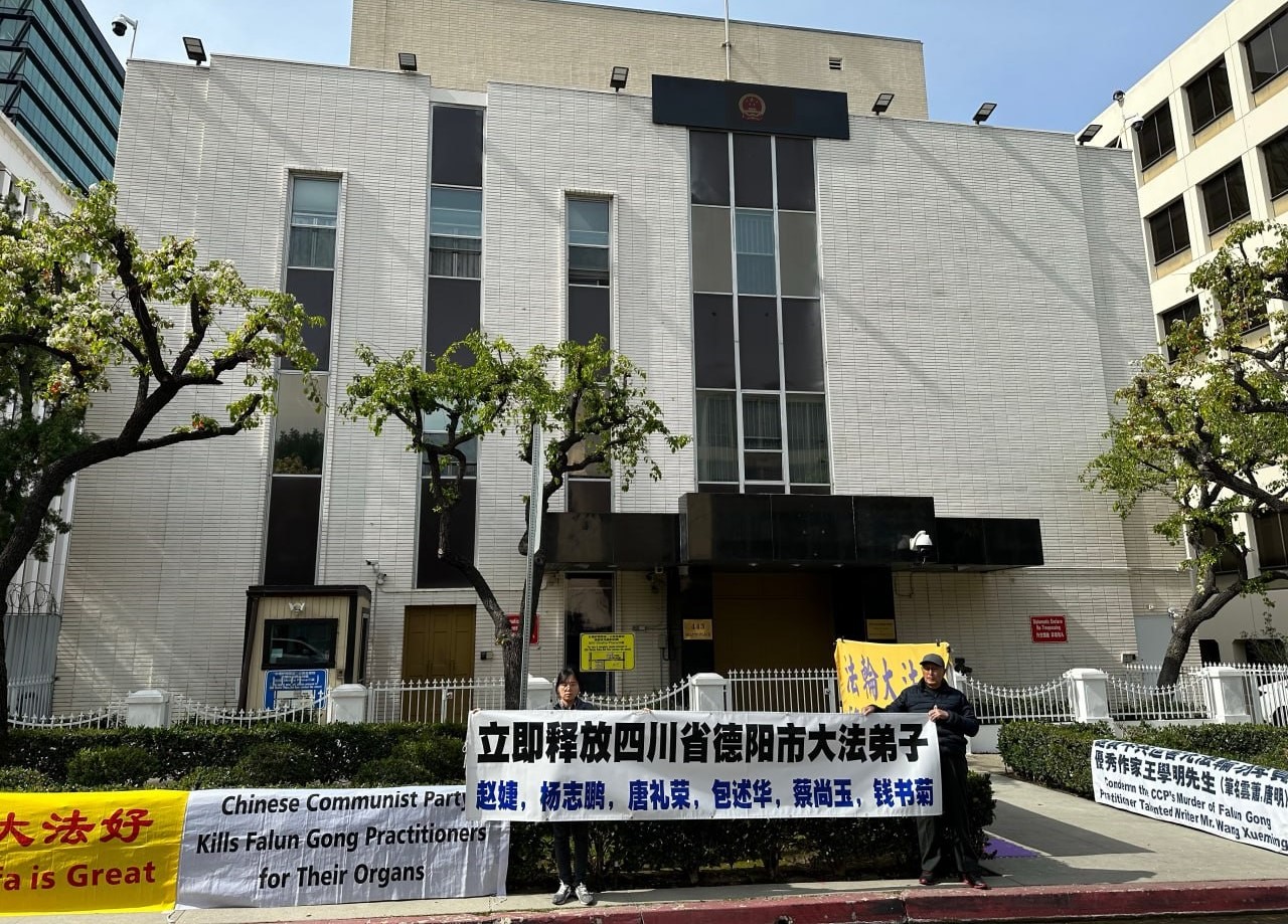 法輪功學員唐瑞（左）在洛杉磯中共領館前舉起橫幅，呼籲立即釋放四川德陽市法輪大法學員。（唐瑞提供）