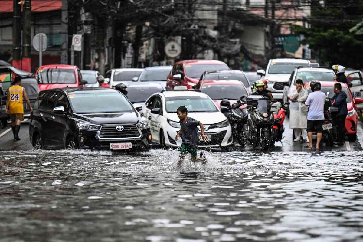 2026年8月17日，在菲律賓首都馬尼拉，多條街道因短時強降雨而嚴重積水，民眾被迫涉水而行。（Jam Sta Rosa/AFP via Getty Images）