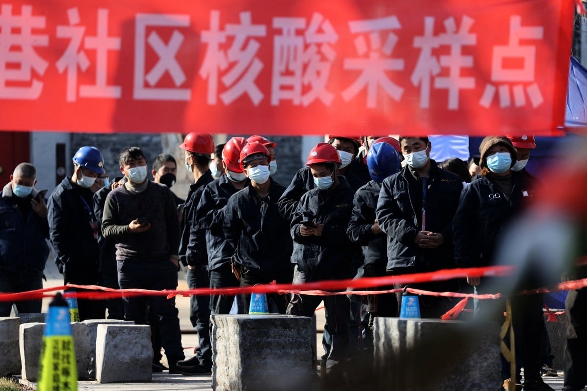 2021年12月21日，在陝西省西安市疫情期間，一些建築工人在排隊等候接受核酸檢測。（STR/AFP via Getty Images）