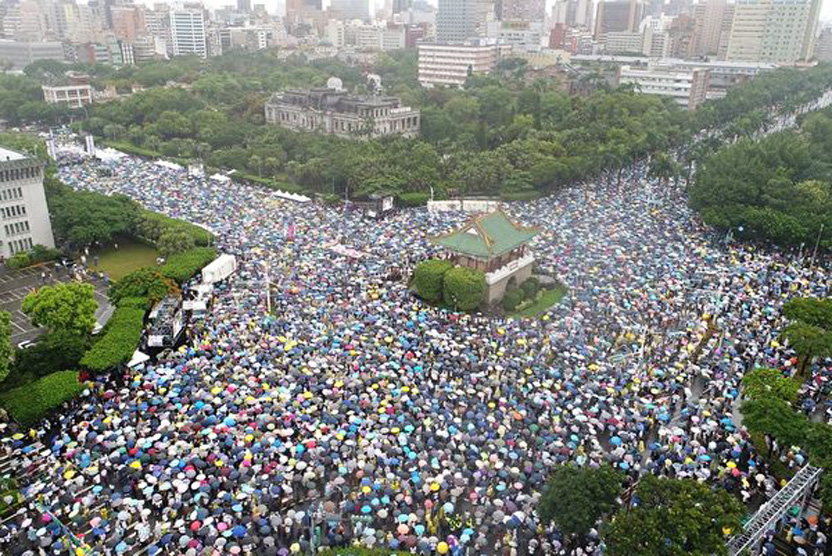 「拒絕紅色媒體、守護台灣民主」活動6月23日下午在總統府前凱達格蘭大道登場，大批民眾冒雨到場響應，舉出標語表達訴求。（大紀元）