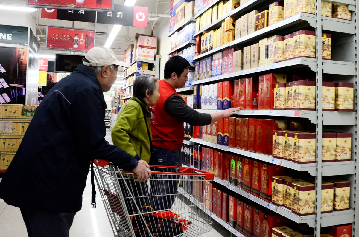 圖為2012年11月20日，北京一家超市的推銷員在向一對老夫婦推銷白酒。（WANG ZHAO/AFP）
