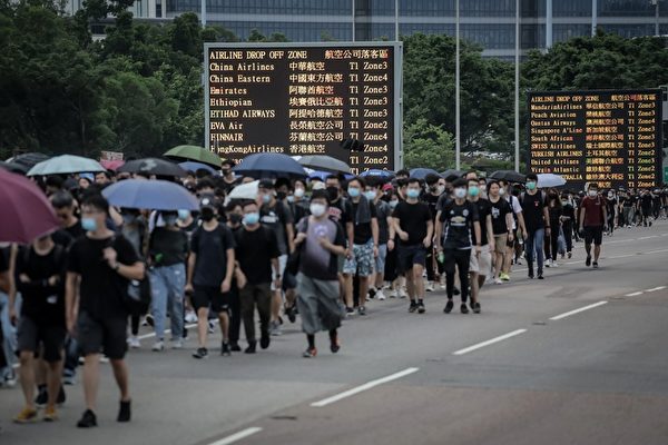 2019年8月12日，進入機場方向的交通塞爆，有的士及巴士乘客提早下車，步行入機場內。（VIVEK PRAKASH/AFP）