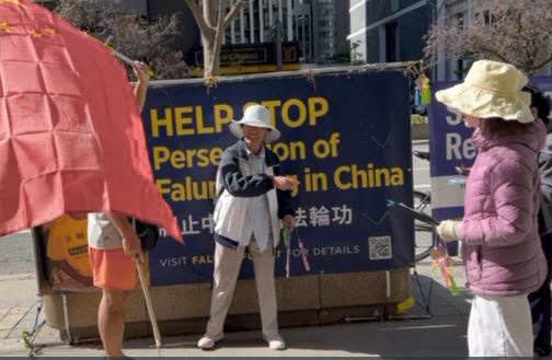 2025年10月2日下午,一位華人在中共駐多倫多領事館簽證處前(393 University Avenue, Toronto)騷擾法輪功學員。他一手舉著中共國旗,另一手拿著一根棍子,猛擊寫有「制止中共迫害法輪功」的橫額。(潘學峰提供)