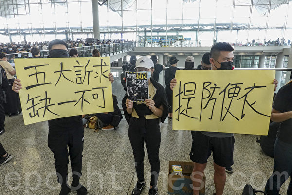 2019年8月12日，港人在香港機場展開「警察還眼」集會。圖為示威民眾舉著「五大訴求 缺一不可」、「提防便衣」等展板和傳單表達訴求。（余鋼／大紀元）
