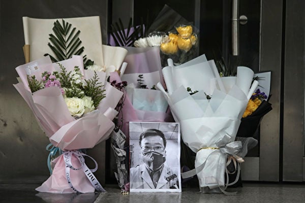 圖為2020年2月7日，湖北武漢市中心醫院外，民眾放置李文亮醫師的遺照及鮮花表達哀悼。（Getty Images）