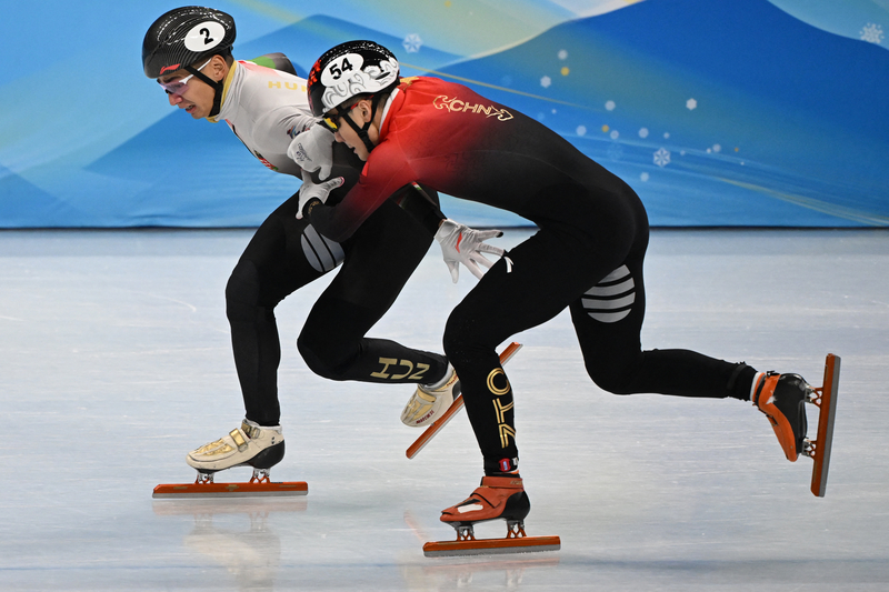 2月7日，2022年北京冬奧會短道速滑男子1000米決賽中，匈牙利選手劉少林（左）與中國選手任子威（右）於終點線前競爭。（MANAN VATSYAYANA/AFP via Getty Images）