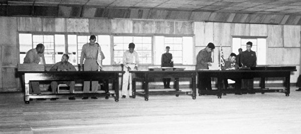 1953年7月27日，聯合國軍代表團首席代表、美國陸軍中將哈里森（William K. Harrison，左側座位上），和北韓軍隊大將南日（右側座位上）簽署停戰協定。中共軍隊作為主要參戰一方，卻沒法簽字。（公有領域）
