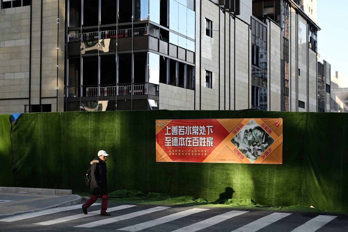 北京說，打擊房地產是為了保持可負擔性住房。但它也同時破壞了房地產開發業的穩定並威脅到經濟增長。圖為2021年10月19日，一名男子經過北京的一處建築工地。（Greg Baker/AFP via Getty Images）