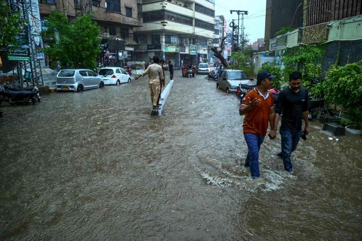 2025年7月14日,巴基斯坦信德省海得拉巴市(Hyderabad)遭暴雨襲擊後,民眾被迫涉水出行。(Jan Ali Laghari/Middle East Images/AFP via Getty Images)