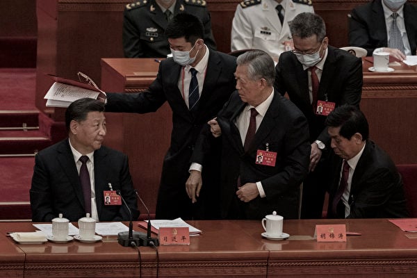 2022年10月22日，在北京人民大會堂，中共國家主席習近平（左）看著前國家主席胡錦濤在中共二十大閉幕式上被工作人員帶離會場。（Kevin Frayer/Getty Images）