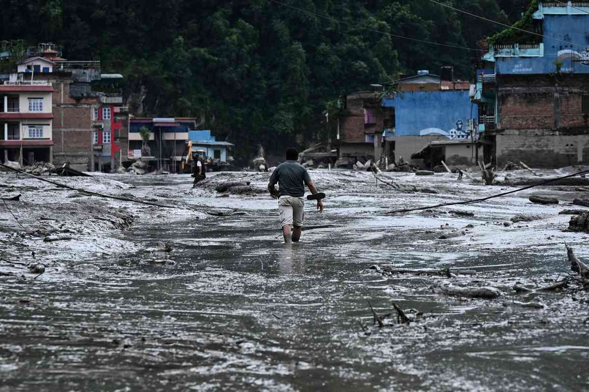 2026年8月26日，在尼泊爾努瓦科特縣（Nuwakot）德夫加特（Devghat）發生山洪，一名居民沿著一條布滿泥水的街道行走。（Prakash Mathema/AFP via Getty Images）